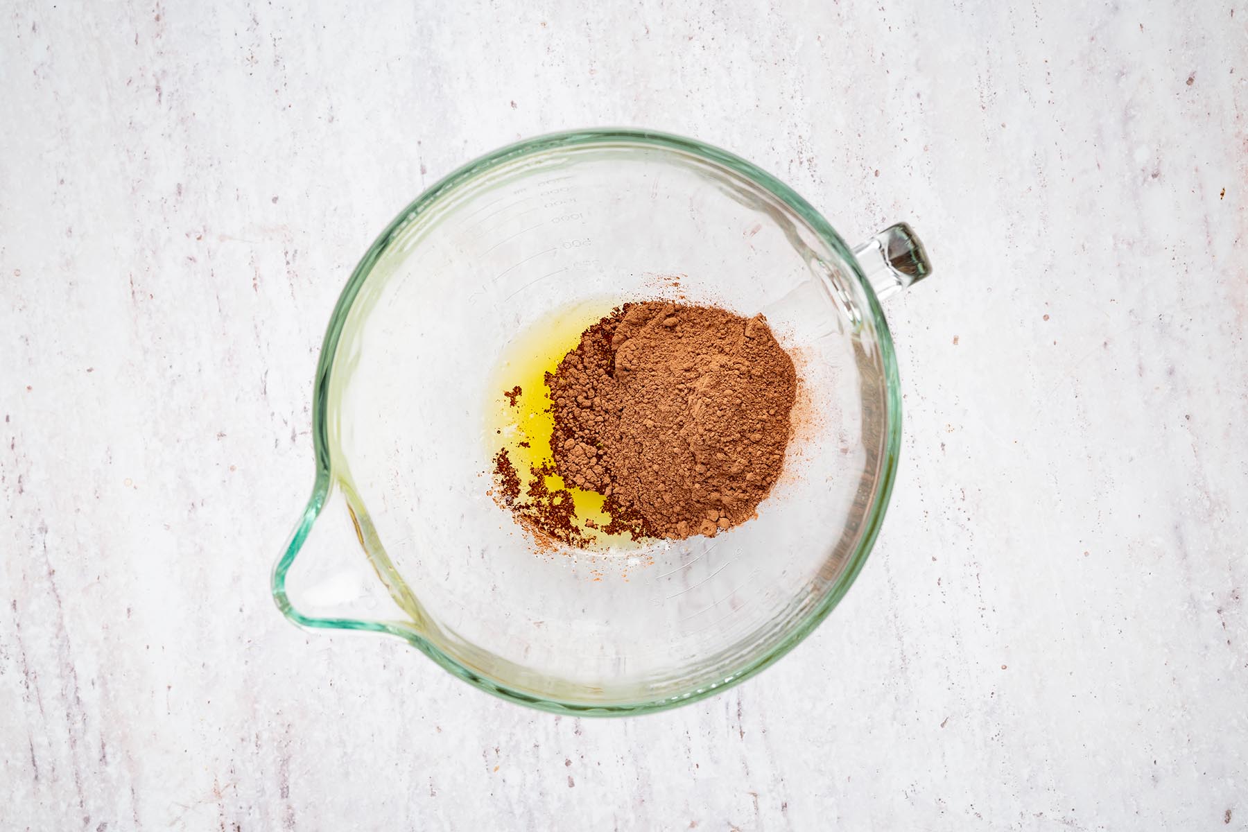Melted butter and cocoa powder added to a glass mixing bowl.