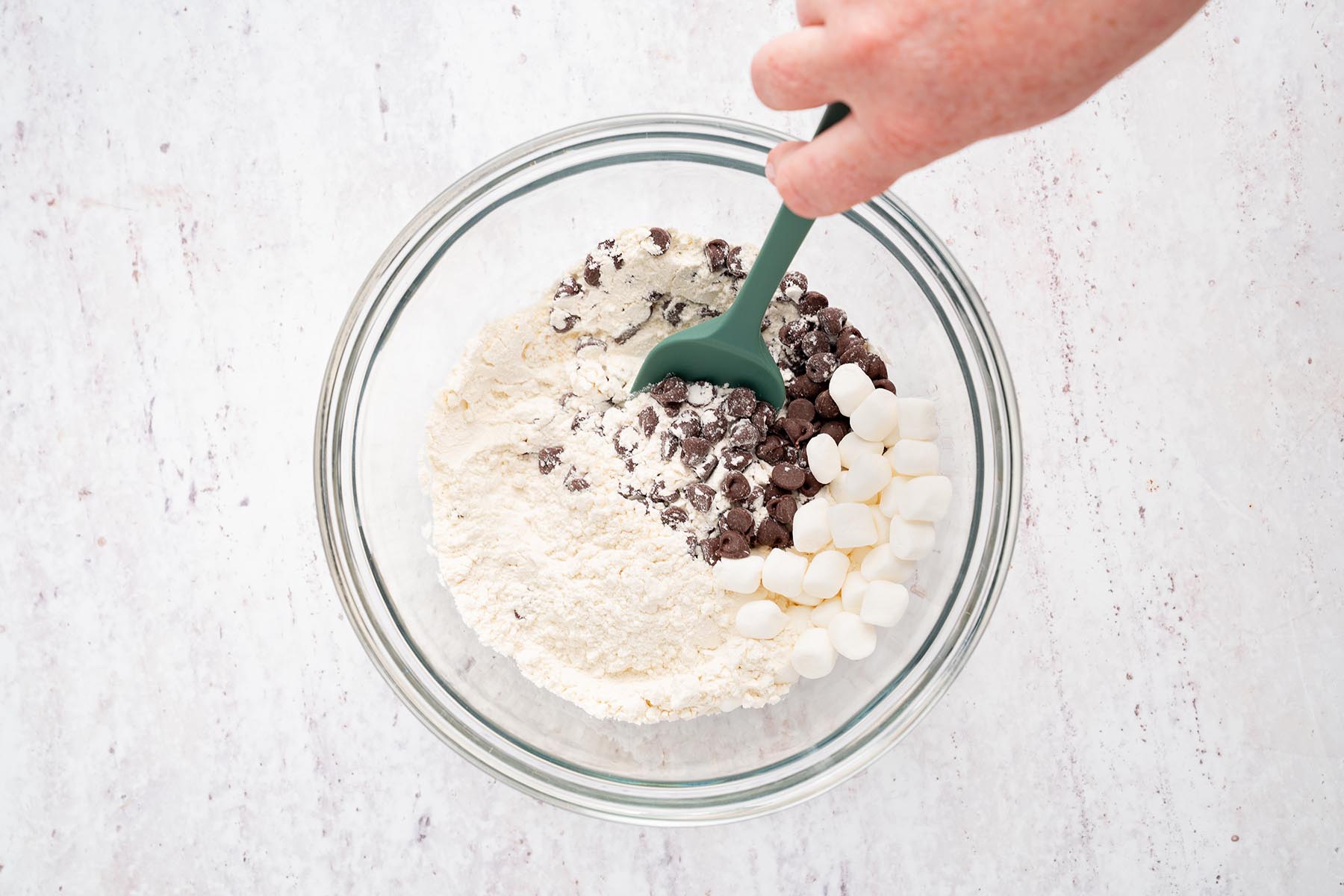 Flour, chocolate chips, and mini marshmallows combined in a glass mixing bowl.