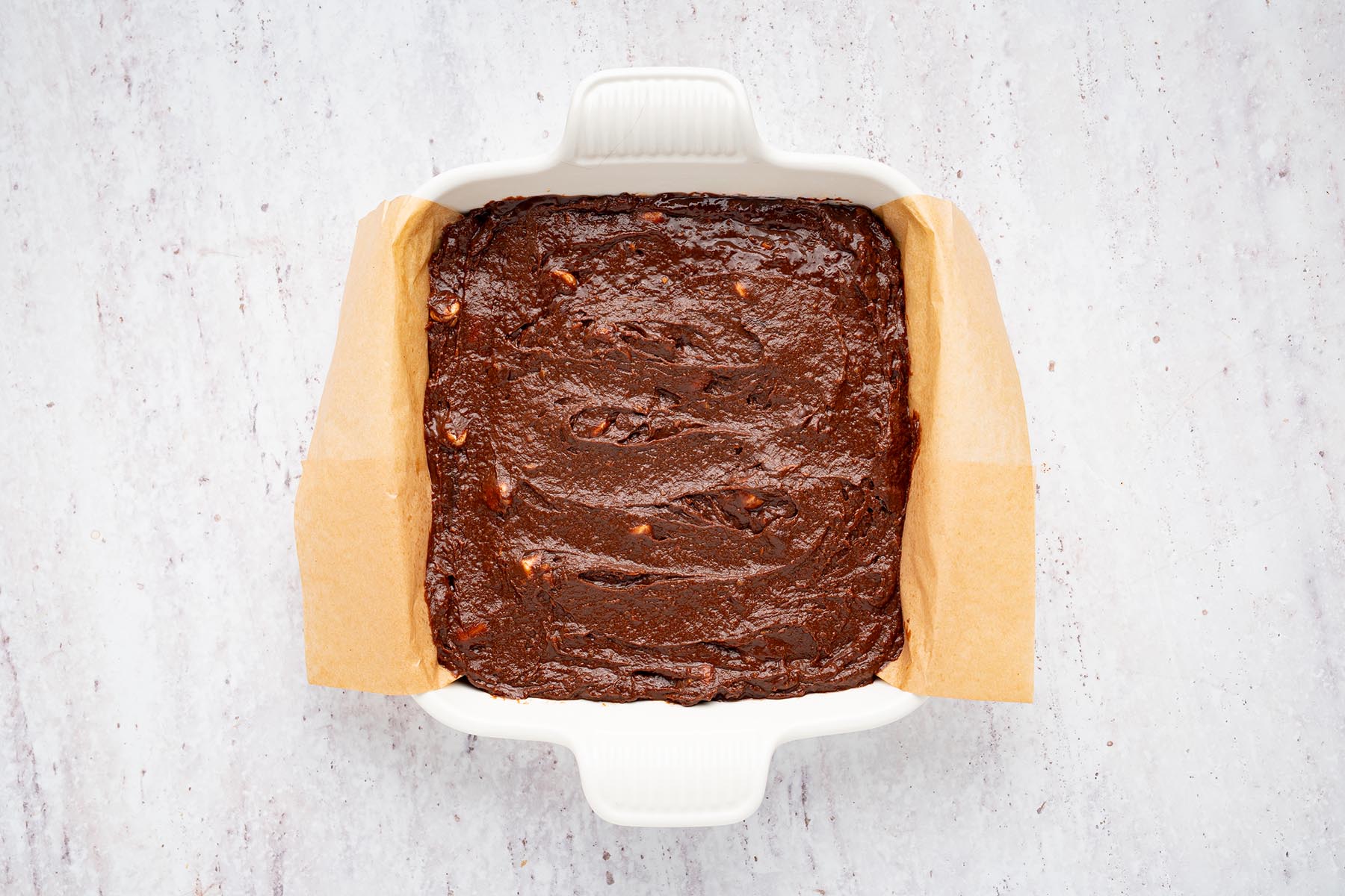 Thick brownie batter spread evenly over a baked graham cracker crust.