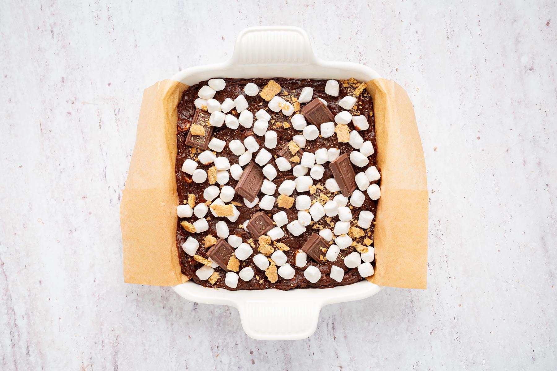 Brownie batter topped with mini marshmallows, milk chocolate pieces, and graham cracker crumbs.