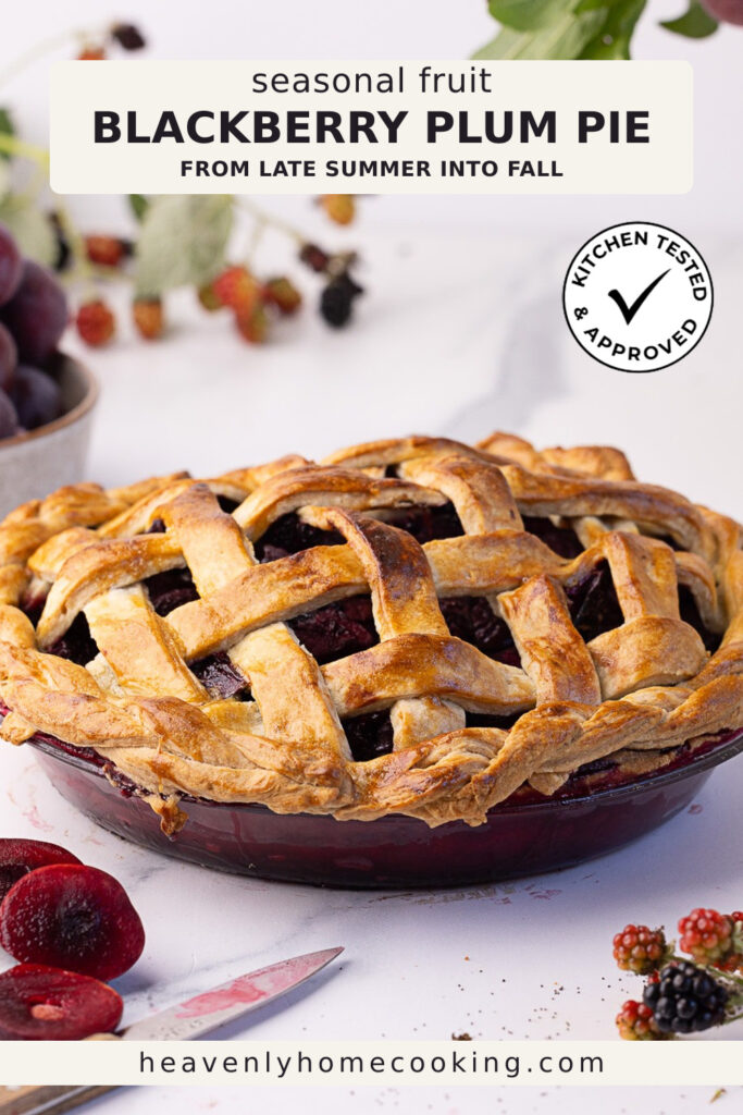 A golden lattice-topped blackberry plum pie filled with juicy seasonal fruit sits on a pie plate, surrounded by fresh plums and blackberries on a light background. This vertical Pinterest pin features a homemade blackberry plum pie recipe from Heavenly Home Cooking.