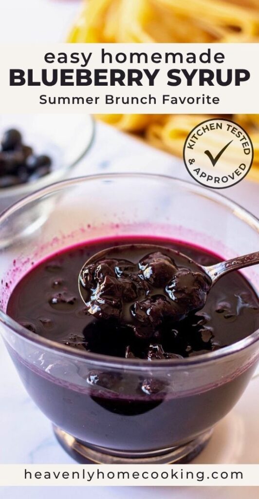 A bowl of homemade blueberry syrup with whole blueberries and a spoon lifting the thick syrup, with fresh blueberries and pancakes softly blurred in the background. This vertical Pinterest pin features a homemade blueberry syrup recipe from Heavenly Home Cooking.