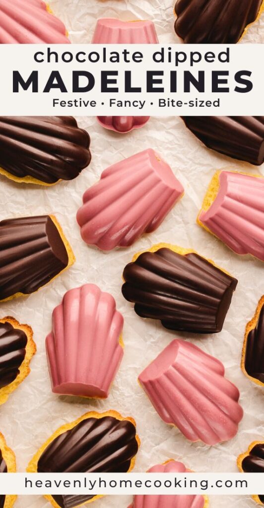 Chocolate-dipped madeleines coated in dark chocolate and pink chocolate are scattered across crinkled parchment paper in a flat lay arrangement. This vertical Pinterest pin features a homemade chocolate dipped madeleines recipe from Heavenly Home Cooking.