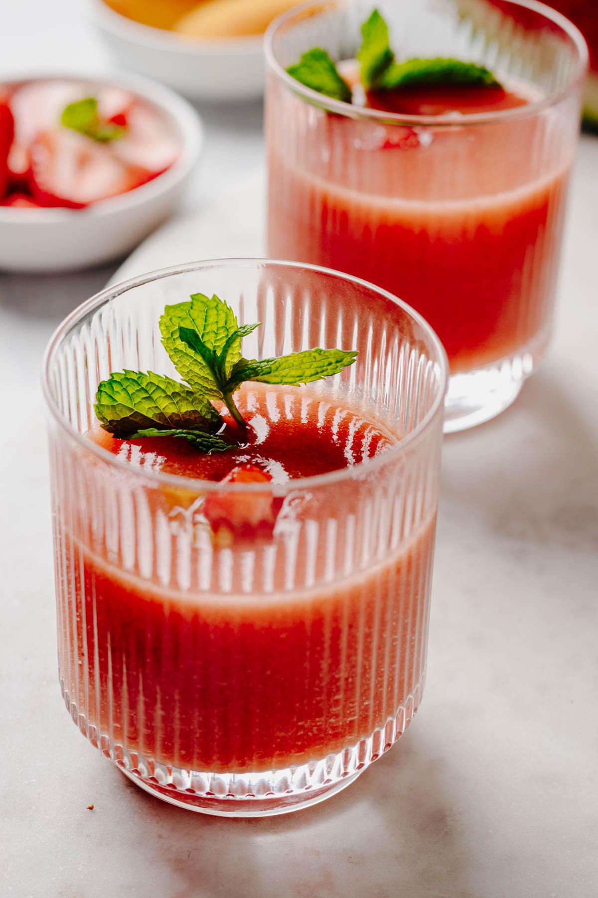 Cold fruit soup served in two fluted glasses and garnished with fresh mint.