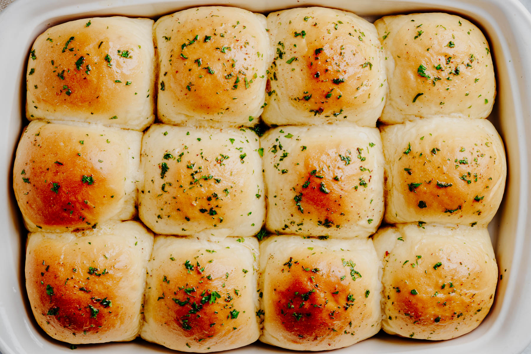 Freshly baked garlic dinner rolls brushed with garlic butter and sprinkled with parsley.
