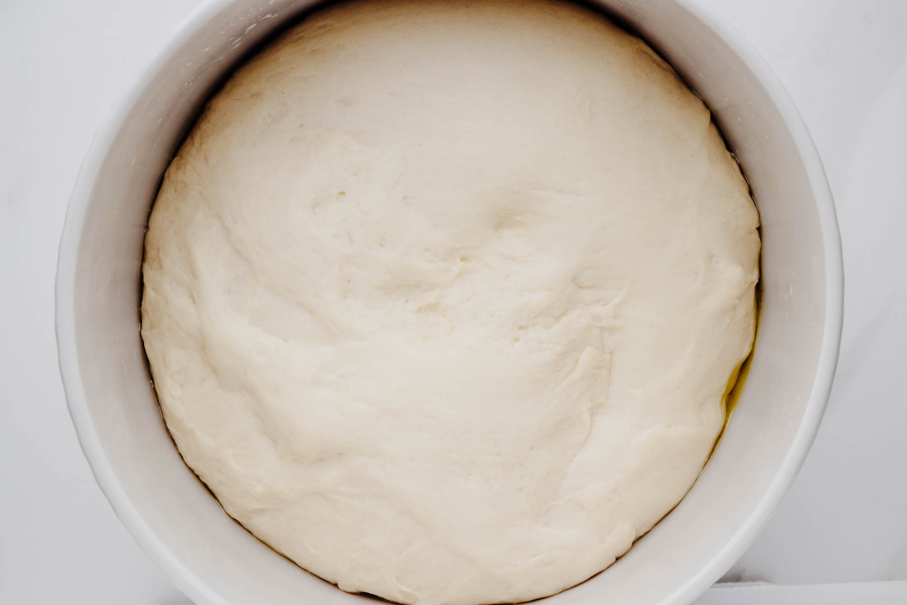 Garlic dinner roll dough after the first rise, doubled in size in a lightly greased bowl.