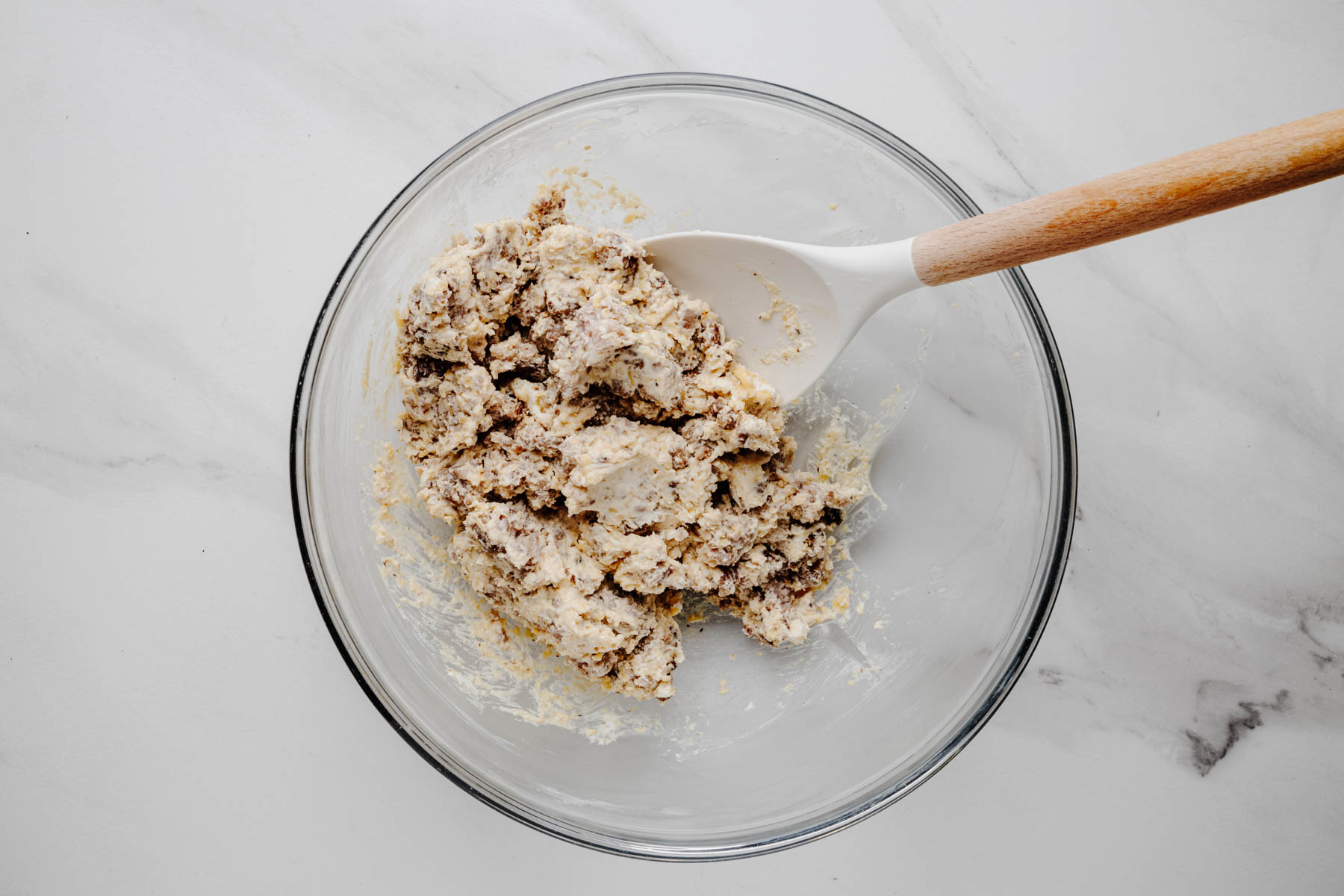 Creamy Italian sausage and cheddar filling mixed in a glass bowl with a silicone spoon.