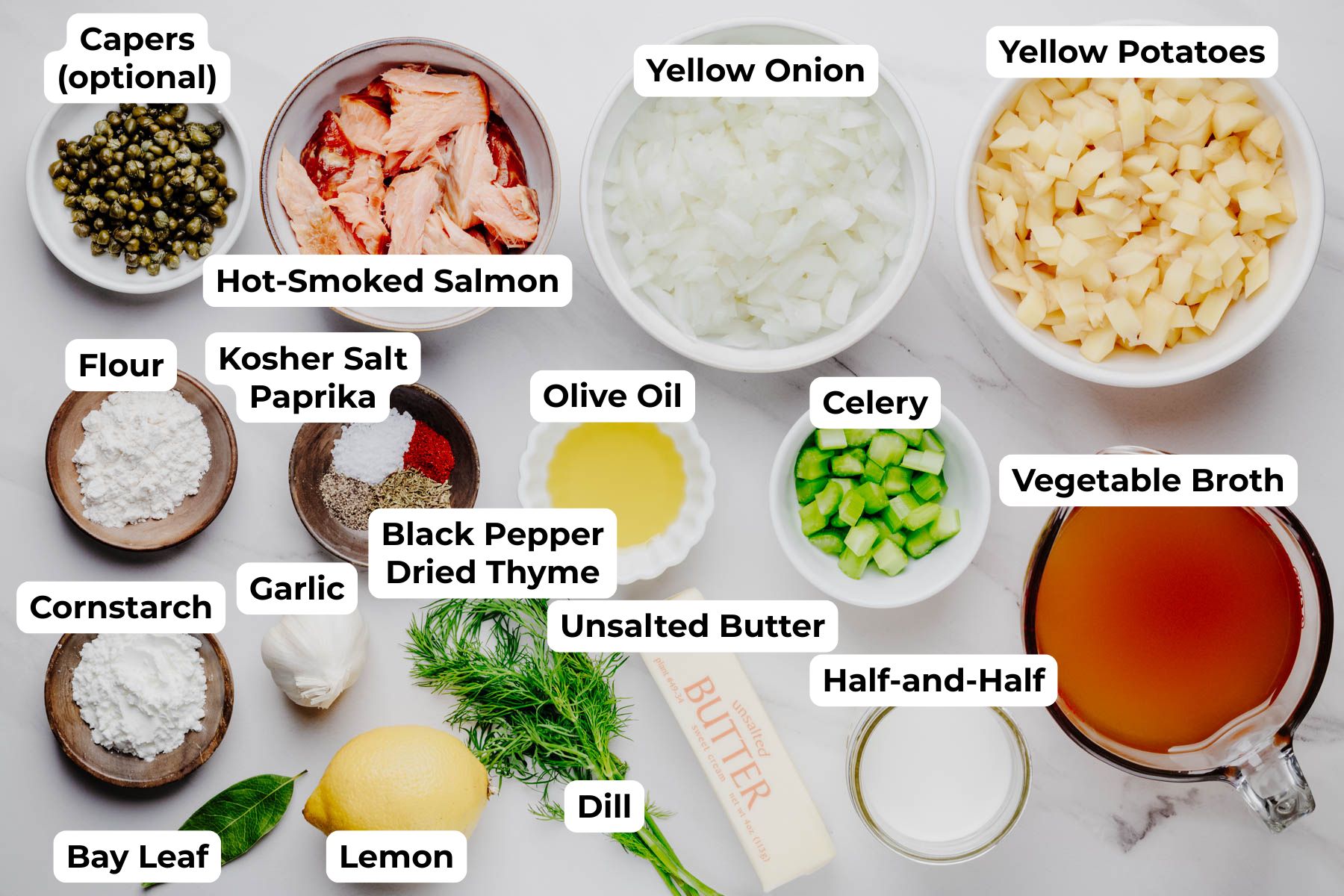 Labeled ingredients for smoked salmon chowder, including hot-smoked salmon, yellow potatoes, vegetable broth, half-and-half, onion, celery, dill, capers, lemon, and seasonings.