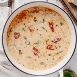 Overhead view of creamy smoked salmon chowder with salmon pieces, capers, and fresh dill in a white Dutch oven.