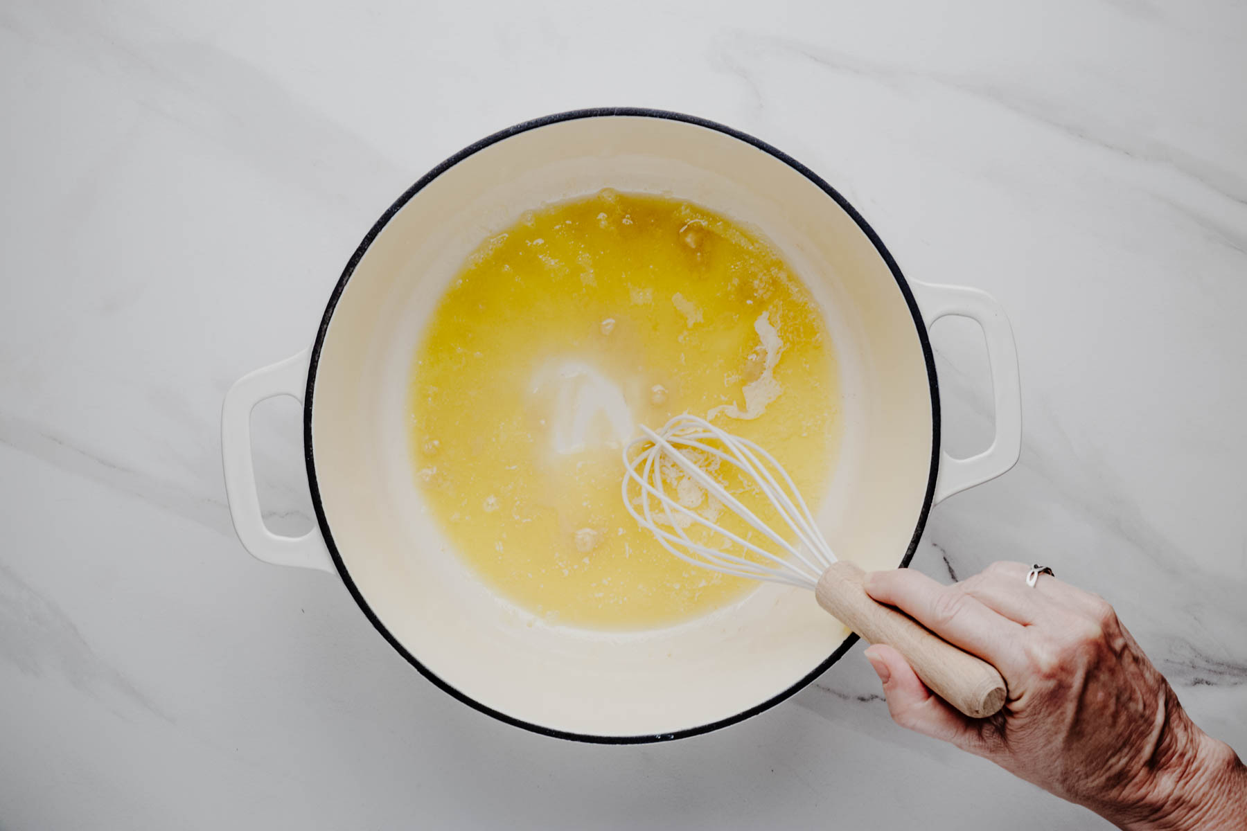 Flour being whisked into melted butter and olive oil to make a roux for smoked salmon chowder.