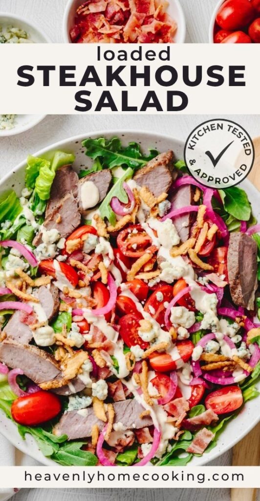 A vertical Pinterest pin featuring a loaded steakhouse salad made with sliced steak, crisp greens, cherry tomatoes, blue cheese, quick pickled red onions, bacon, crispy fried onions, and creamy dressing. The pin is titled "Loaded Steakhouse Salad," includes the Heavenly Home Cooking Kitchen Tested & Approved badge, and features the Heavenly Home Cooking website at the bottom.