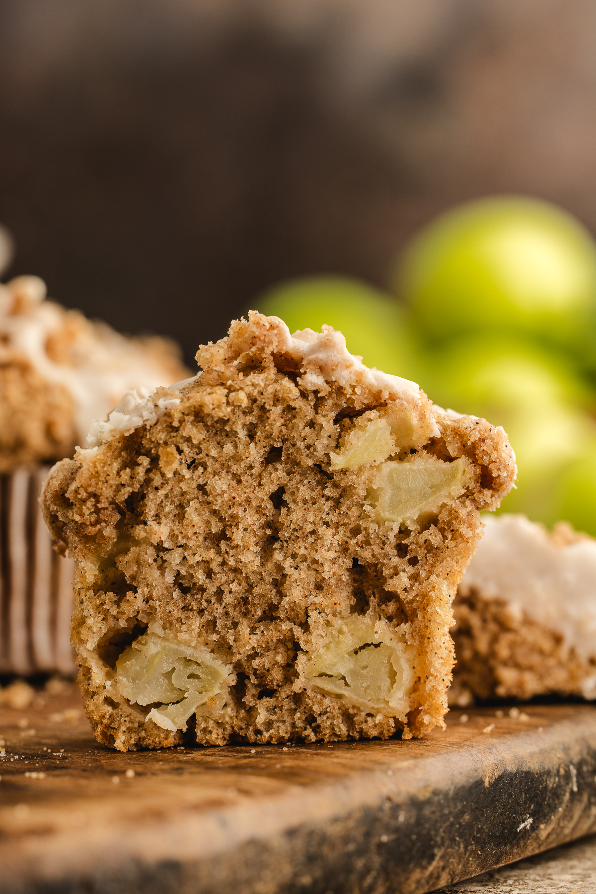 Cut-open apple streusel muffin showing tender cinnamon crumb and chunks of apple inside.