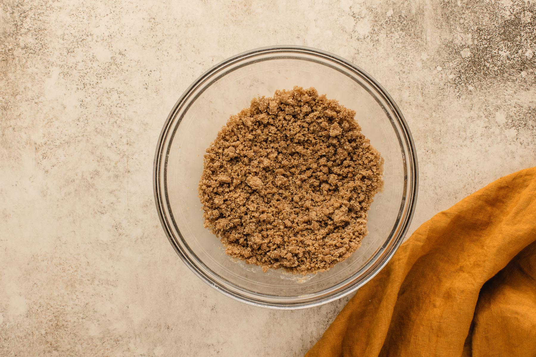 Finished cinnamon brown sugar streusel with coarse crumbs in a glass mixing bowl.