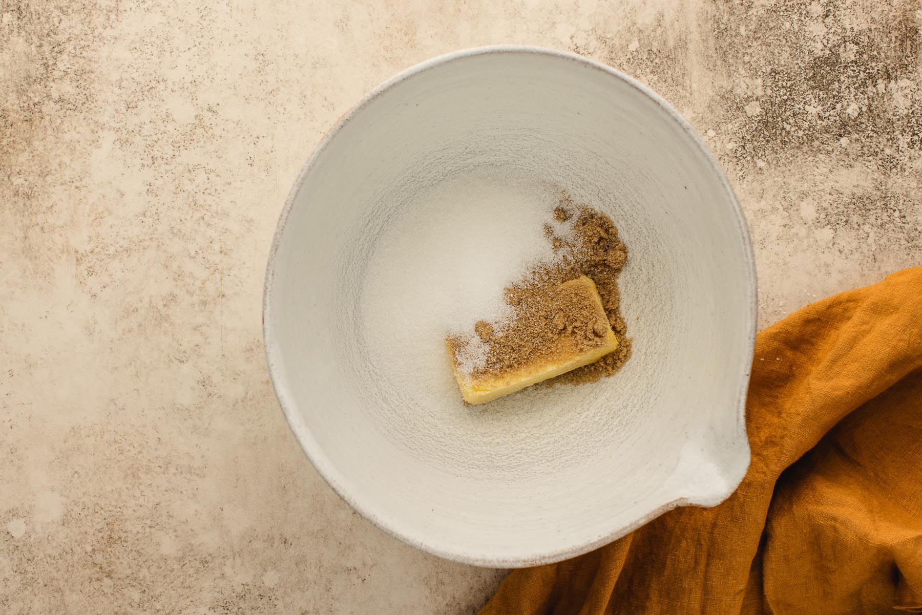 Softened butter with brown sugar and granulated sugar in a large white mixing bowl.