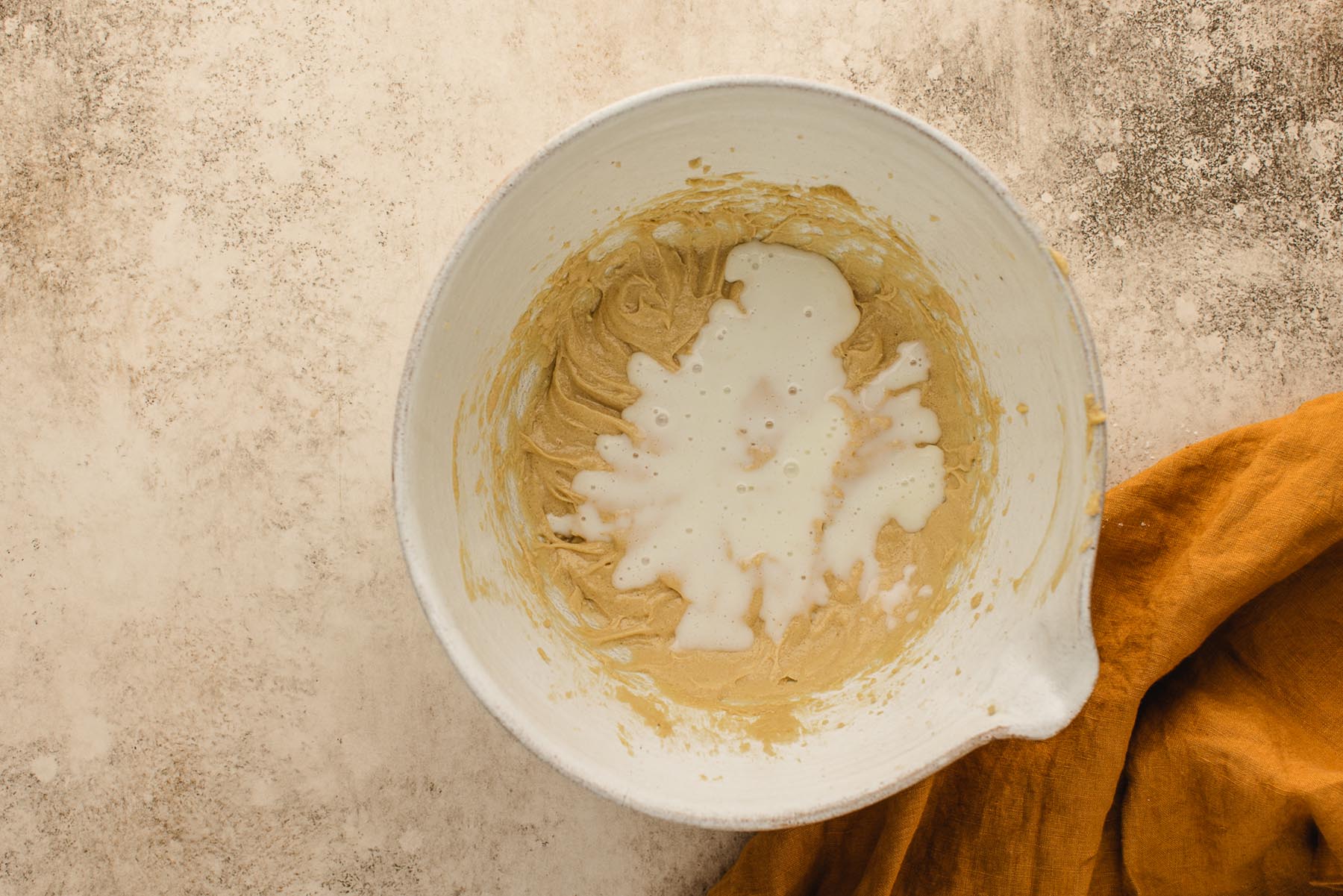 Buttermilk poured over the butter, sugar, and egg mixture for apple muffin batter.