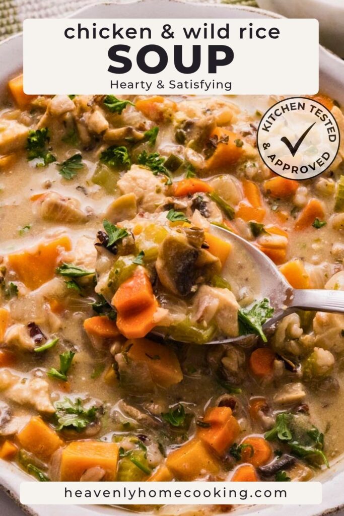 Close-up of creamy chicken and wild rice soup with chicken, carrots, celery, mushrooms, wild rice, and fresh parsley. This is a Pinterest pin for a Heavenly Home Cooking recipe.