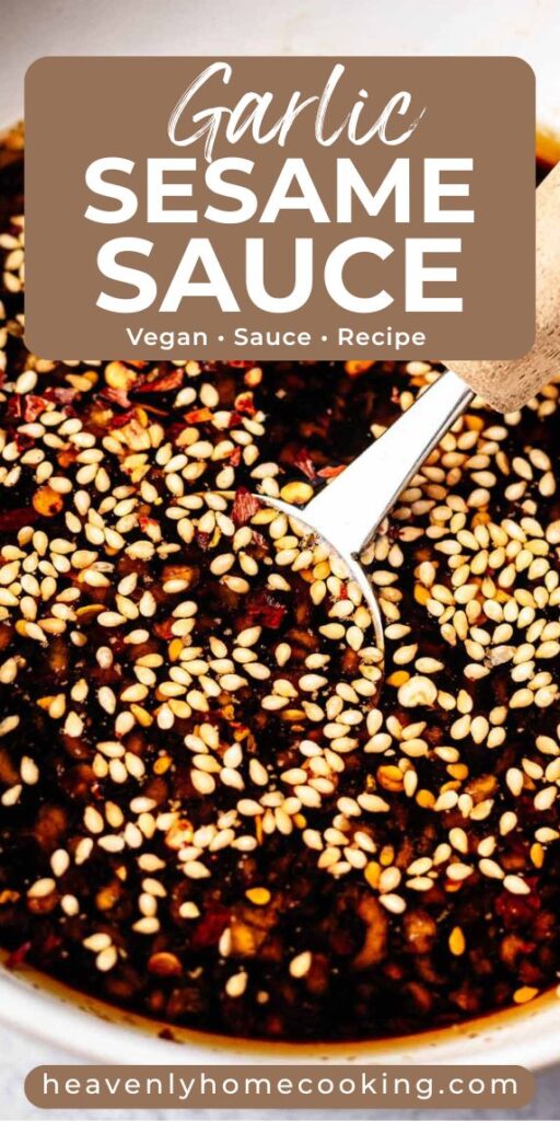 Close-up of dark garlic sesame sauce topped with sesame seeds and red pepper flakes, with a small spoon resting in the sauce. Pin text reads “Garlic Sesame Sauce – Vegan Sauce Recipe” with Heavenly Home Cooking branding.