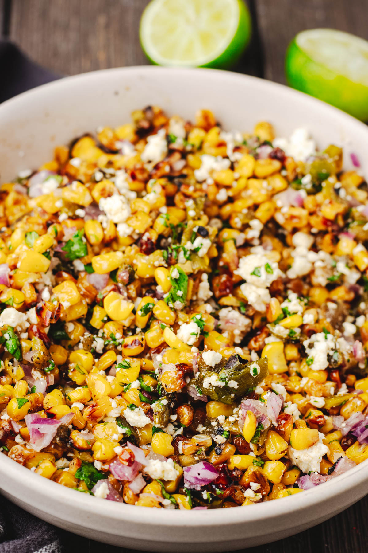 Close-up of Hatch chile corn salad with charred corn, roasted green chiles, Cotija, red onion, cilantro, and lime.