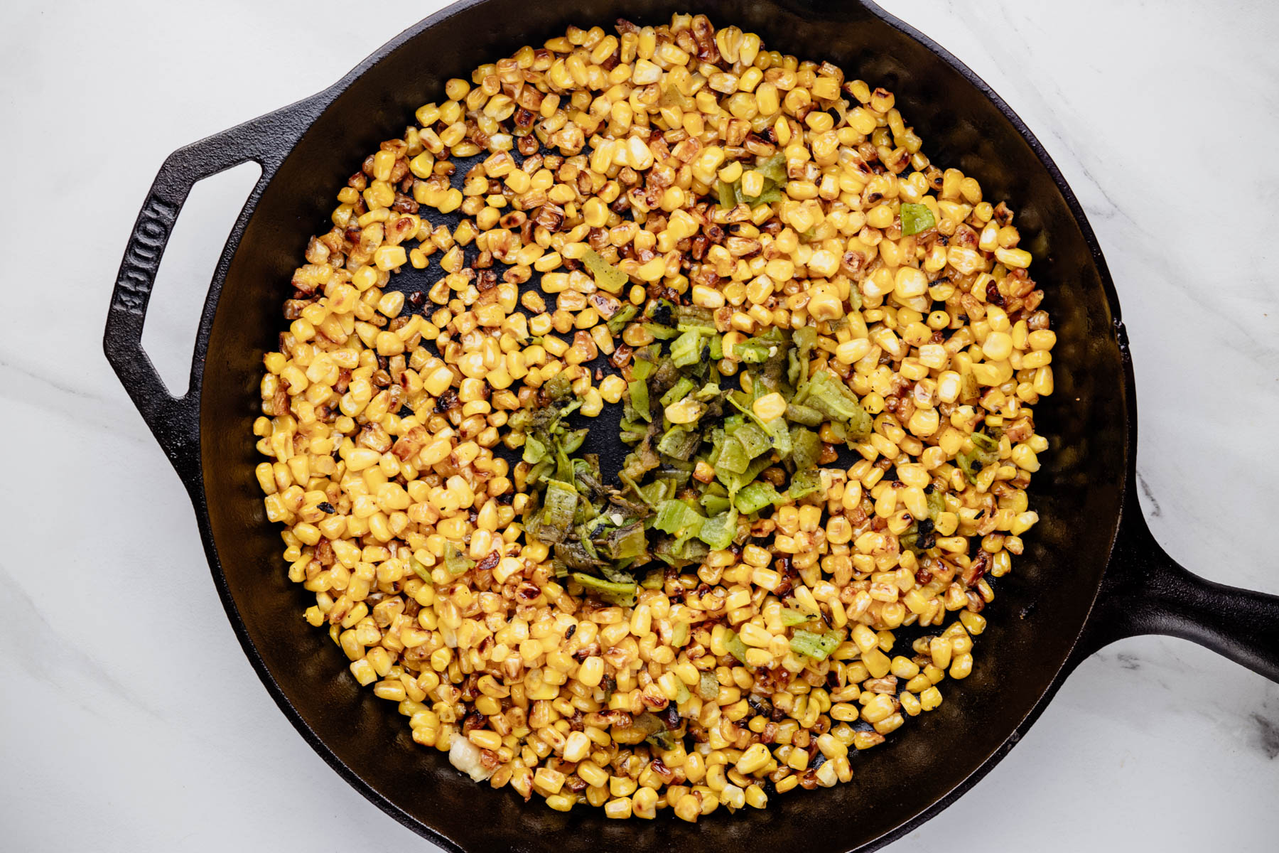 Charred corn and chopped roasted Hatch chiles in a cast-iron skillet.