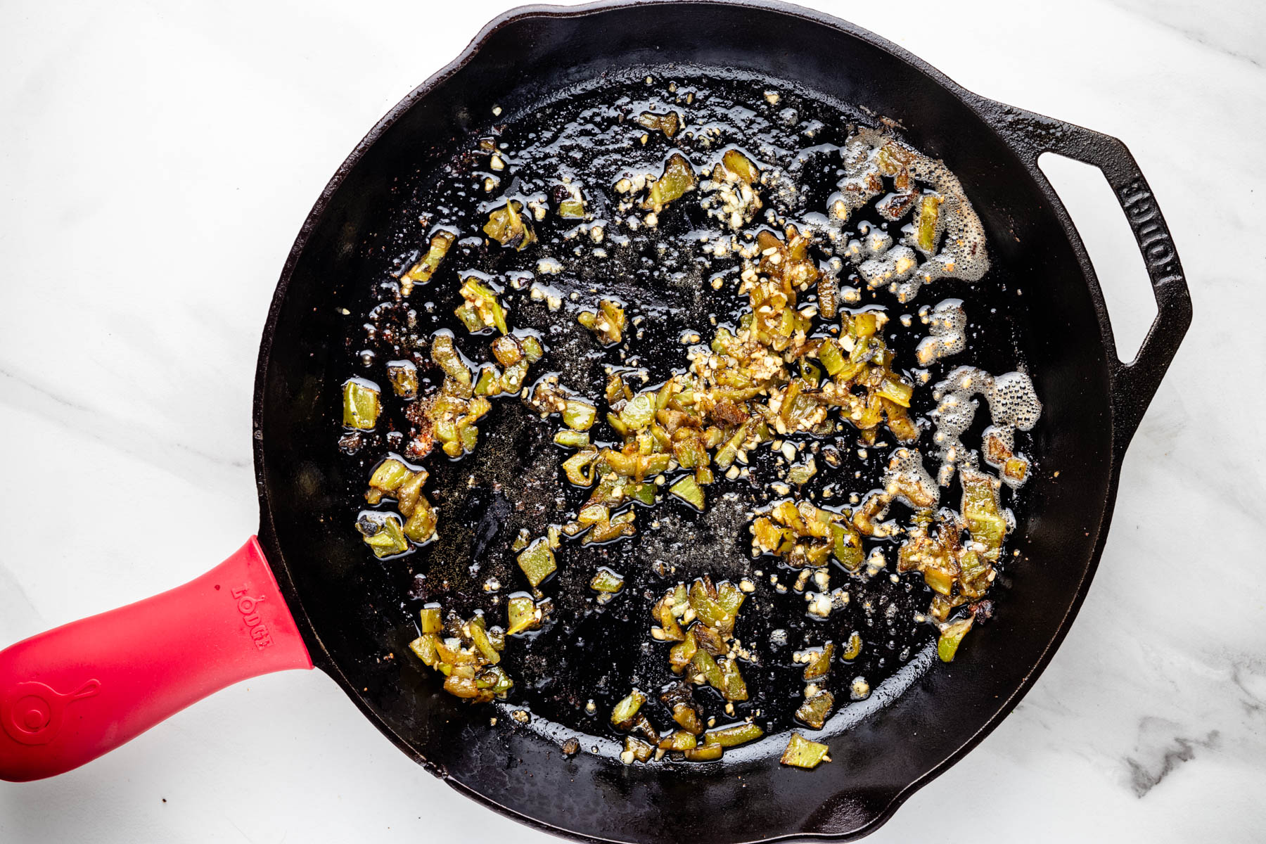 Chopped roasted Hatch chiles and minced garlic sizzling in melted butter in a cast-iron skillet.