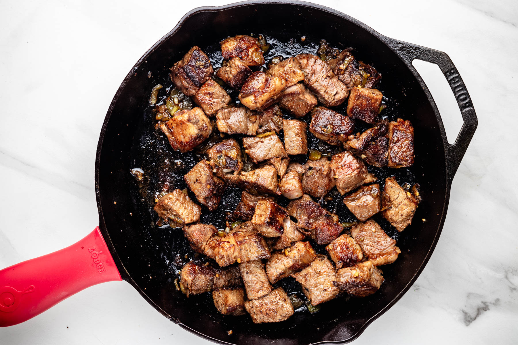 Seared steak bites tossed with Hatch chiles, garlic, and melted butter in a cast-iron skillet.