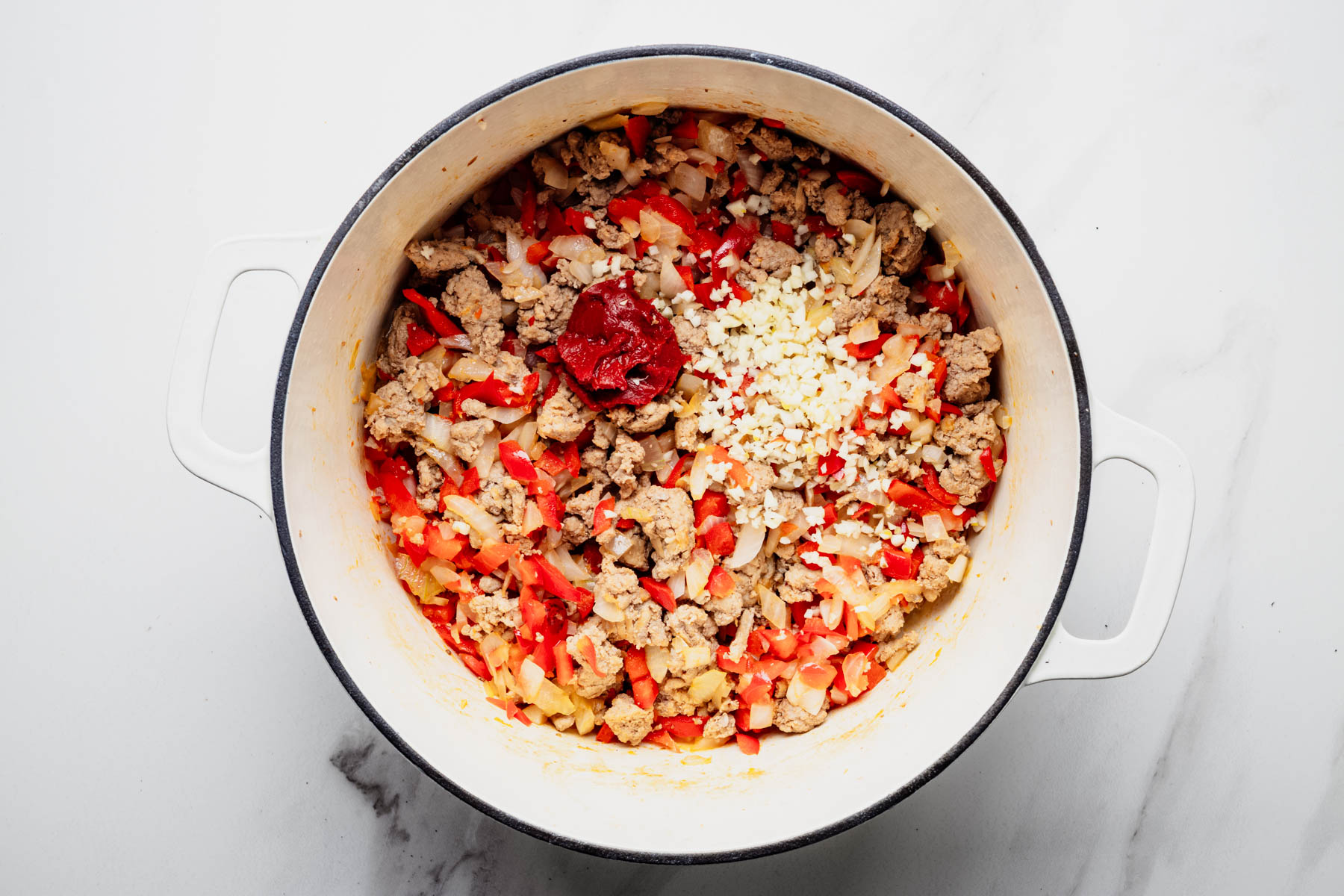 Minced garlic and tomato paste added to cooked ground turkey, onion, and red bell pepper.