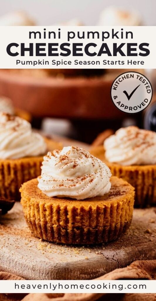 Mini pumpkin cheesecakes topped with swirls of whipped cream and a dusting of pumpkin pie spice on a rustic wooden board. The Pinterest pin reads "Mini Pumpkin Cheesecakes" with the subtitle "Pumpkin Spice Season Starts Here," alongside a Kitchen Tested & Approved badge and Heavenly Home Cooking branding.