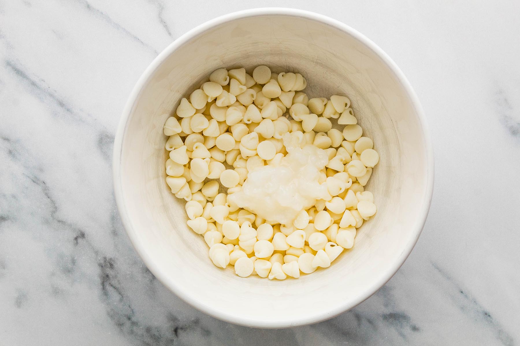 White chocolate chips and coconut oil in a microwave-safe bowl before melting.