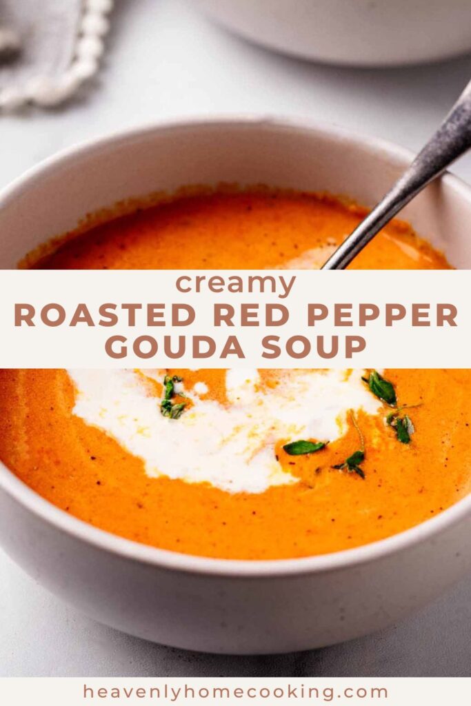 Close-up of creamy roasted red pepper and Gouda soup topped with a swirl of cream and fresh herbs. This is a Pinterest pin for a Heavenly Home Cooking recipe.