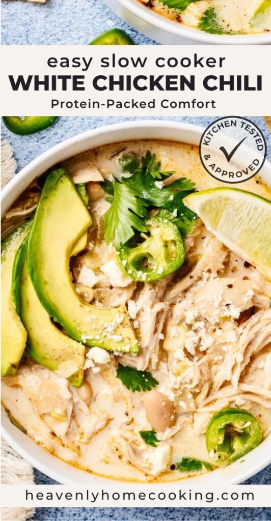 Vertical Pinterest pin for easy slow cooker white chicken chili featuring a close-up bowl of creamy white chicken chili topped with shredded chicken, avocado slices, jalapeños, fresh cilantro, crumbled cheese, and a lime wedge. The text overlay reads "Easy Slow Cooker White Chicken Chili" with the subtitle "Protein-Packed Comfort," and includes a Kitchen Tested & Approved badge and the Heavenly Home Cooking logo.
