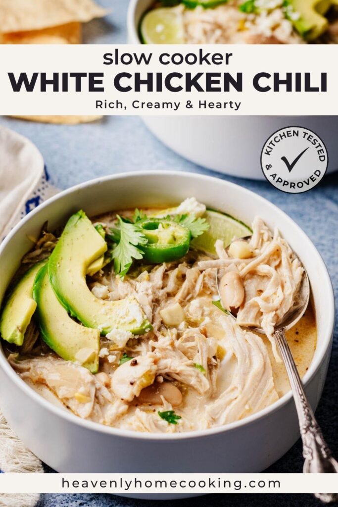 Vertical Pinterest pin for slow cooker white chicken chili featuring a bowl of creamy white chicken chili with shredded chicken, white beans, avocado slices, jalapeños, fresh cilantro, and a lime wedge. The text overlay reads "Slow Cooker White Chicken Chili" with the subtitle "Rich, Creamy & Hearty," and includes a Kitchen Tested & Approved badge and the Heavenly Home Cooking logo.